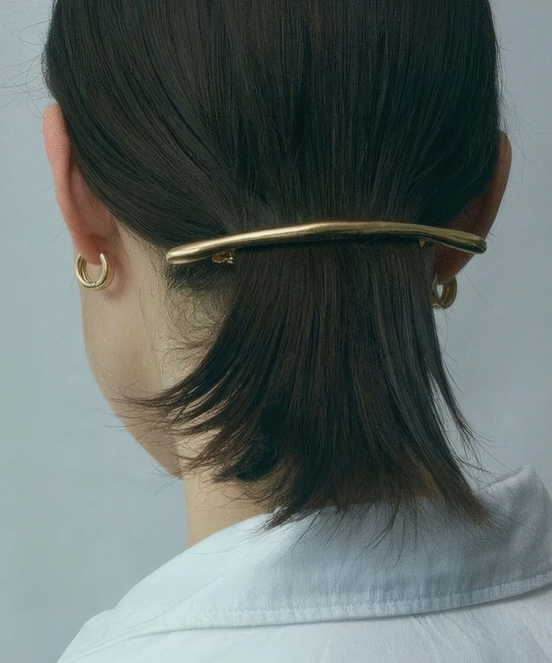 Low ponytail secured with a minimalist hair barrette.