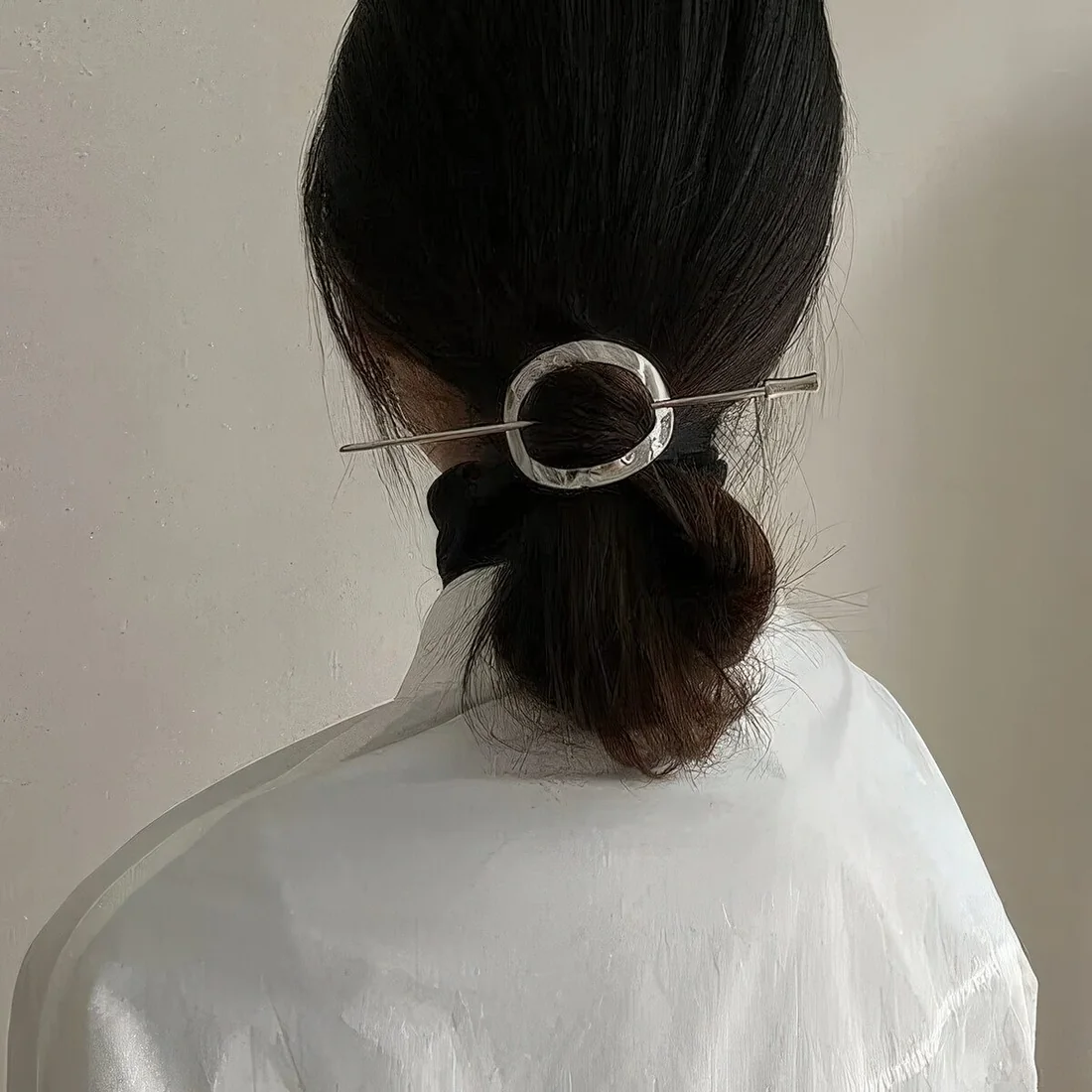 Low poytail with a sleek top and a catchy silver hair piece with a hair pin.