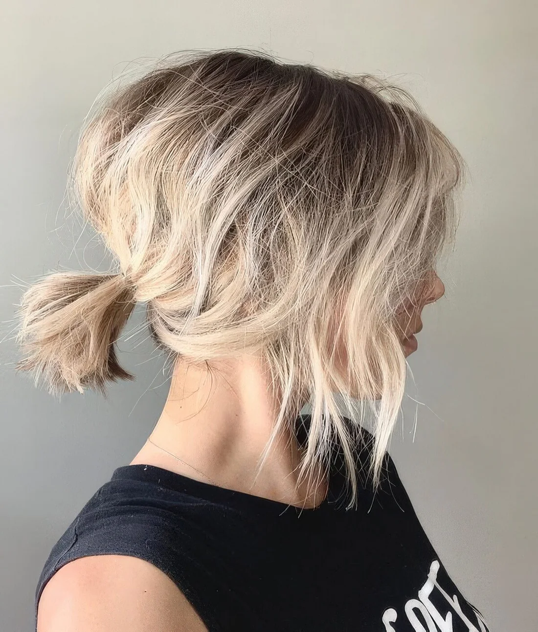Messy and textured low ponytail with a bump and side bangs.