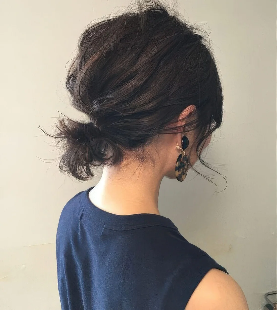 Messy low ponytail with a volumetric bump on top and some side bangs.