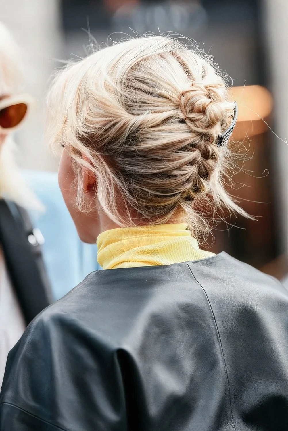 Backward braided updo with a tiny bun on top and some face-framing hair for a cool look.