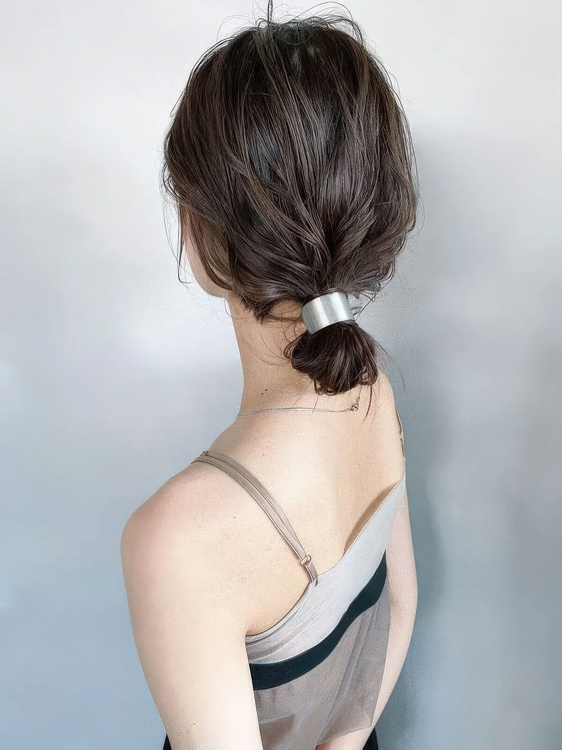 Fast and simple wavy low bun made with a metallic piece and with a messy top.