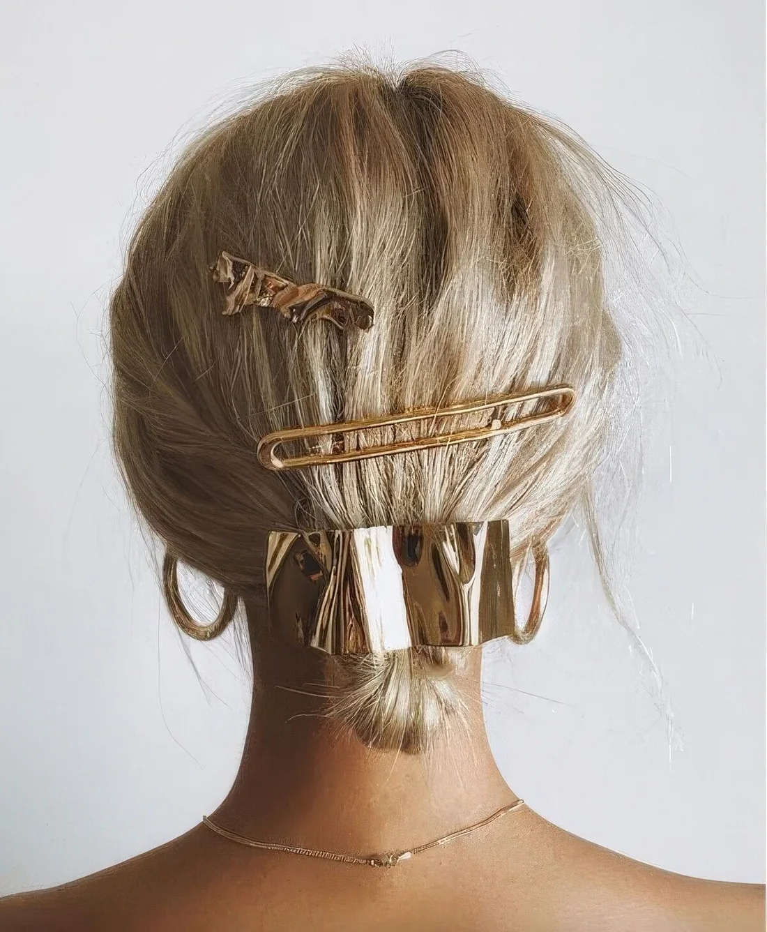 Glam low updo done with gold hair accessories, barrettes and a hair pin.
