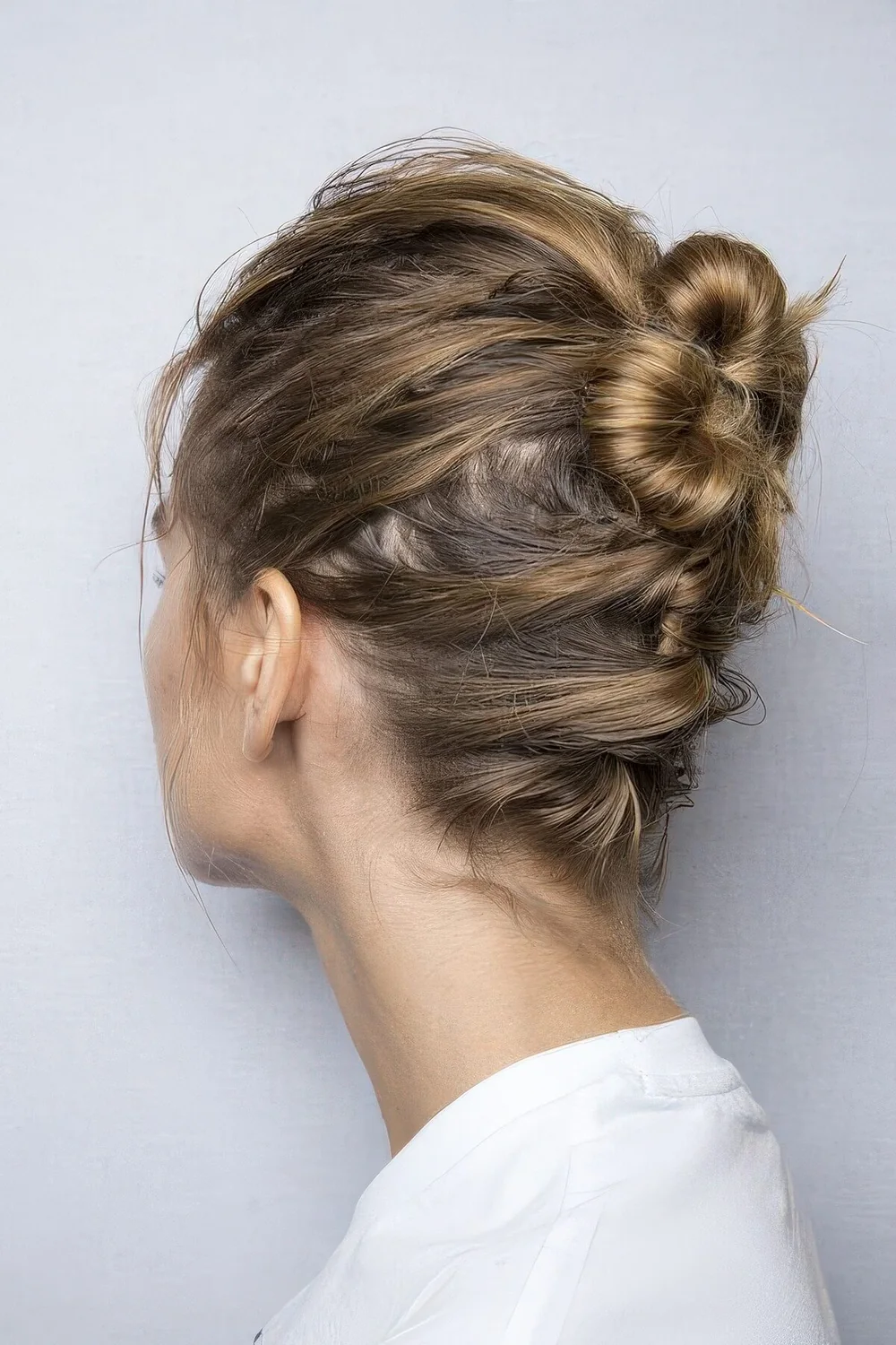 Messy ballerina bun made on top and with messy hair secured to keep it in place.