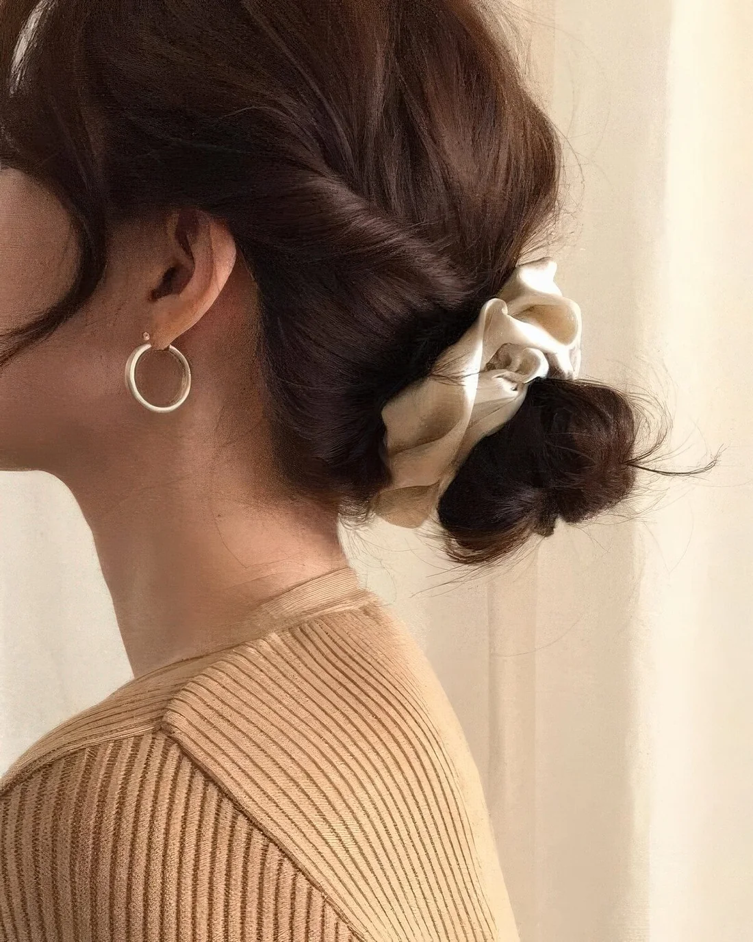 Low bun with twisted hair and face-framing bangs plus a scrunchie.