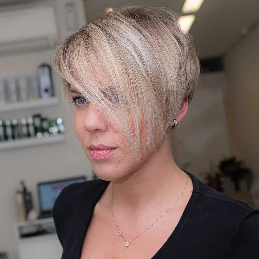 Blonde pixie haircut with icy highlights and long side bangs that.