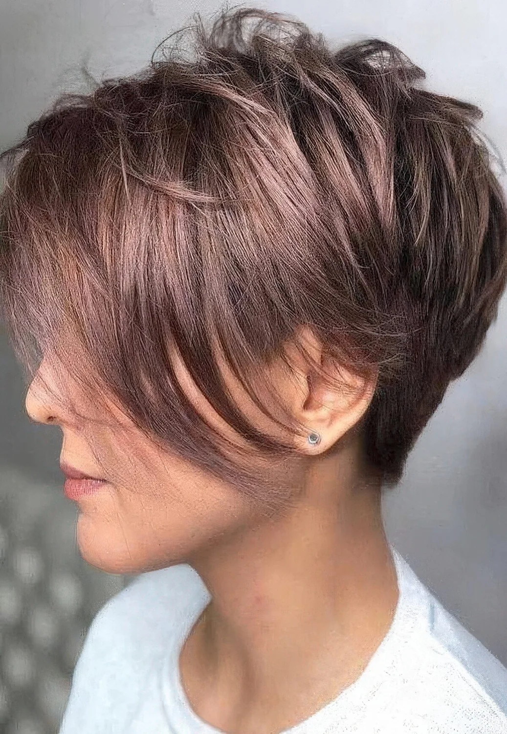 Shiny mauve pixie haircut with a long fringe.
