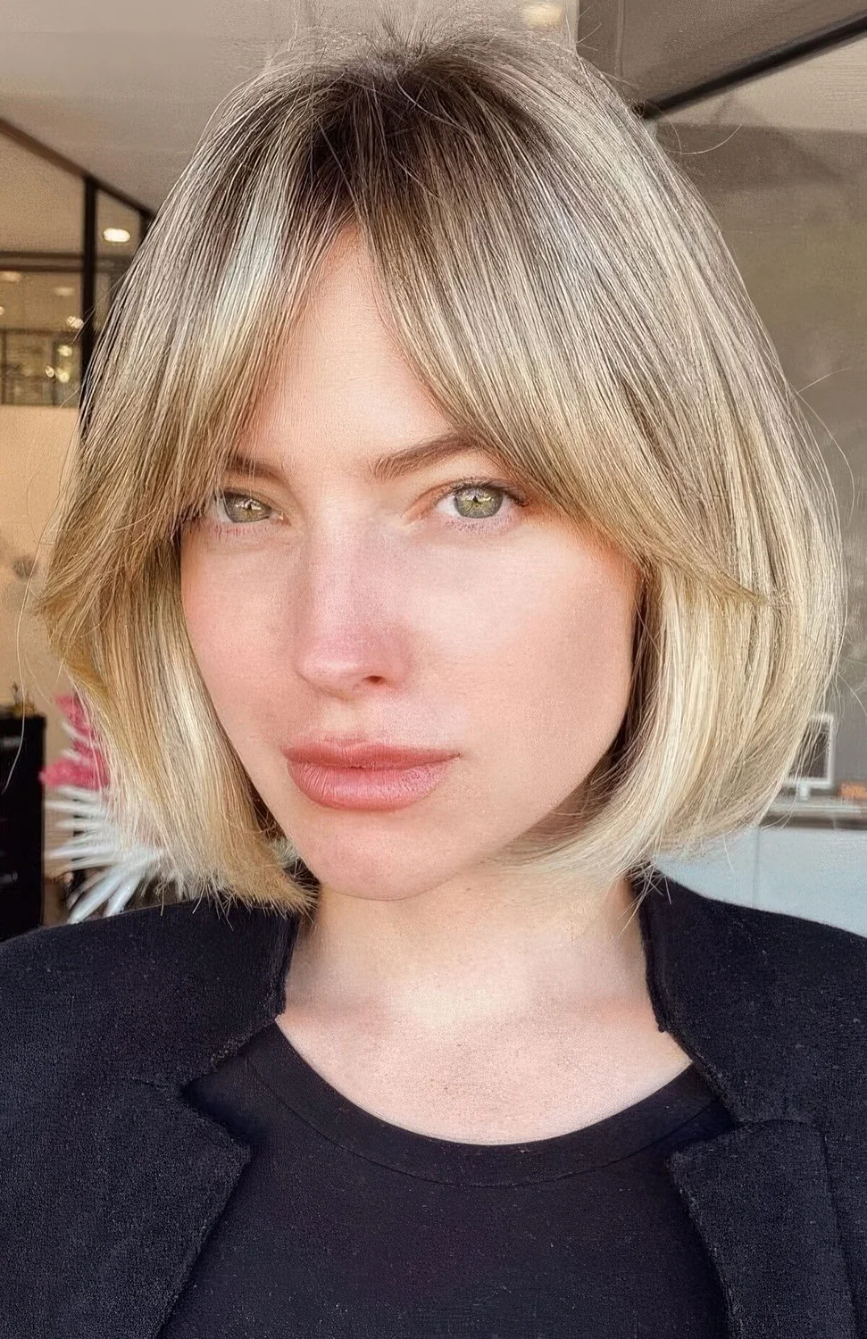 Blonde bob with a darker root and soft curtain bangs.