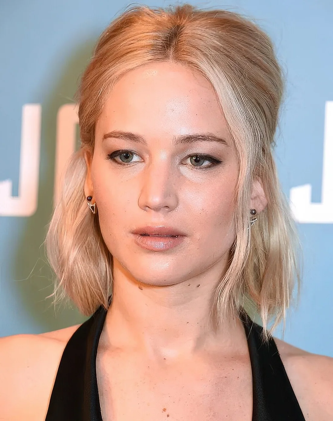 Blonde midi bob styled as a half updo, with some face-framing hair.