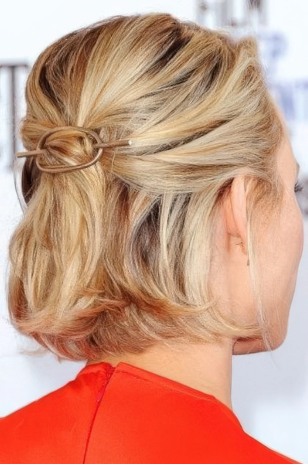 Midi blonde bob styled as a half updo, with a bump on top and a hair piece, with some volume on top.