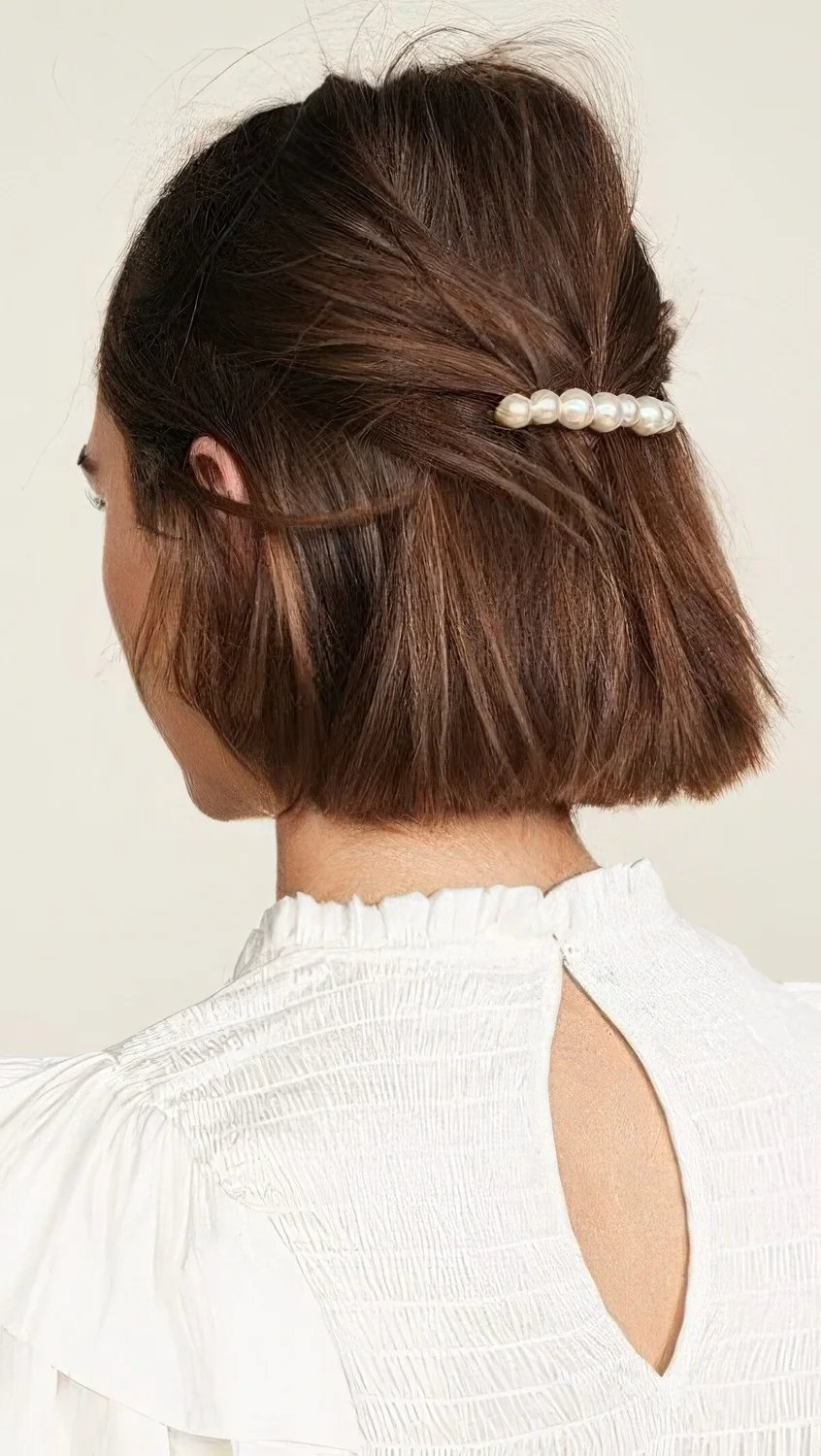 Midi bob styled as a half updo, with an elegant pearl barrette.