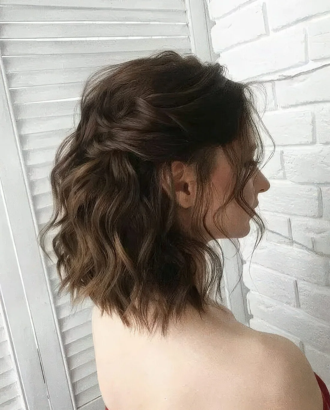 Dark brown medium-length wavy half-up hairstyle with a wavy top, locks framing the face and waves down.