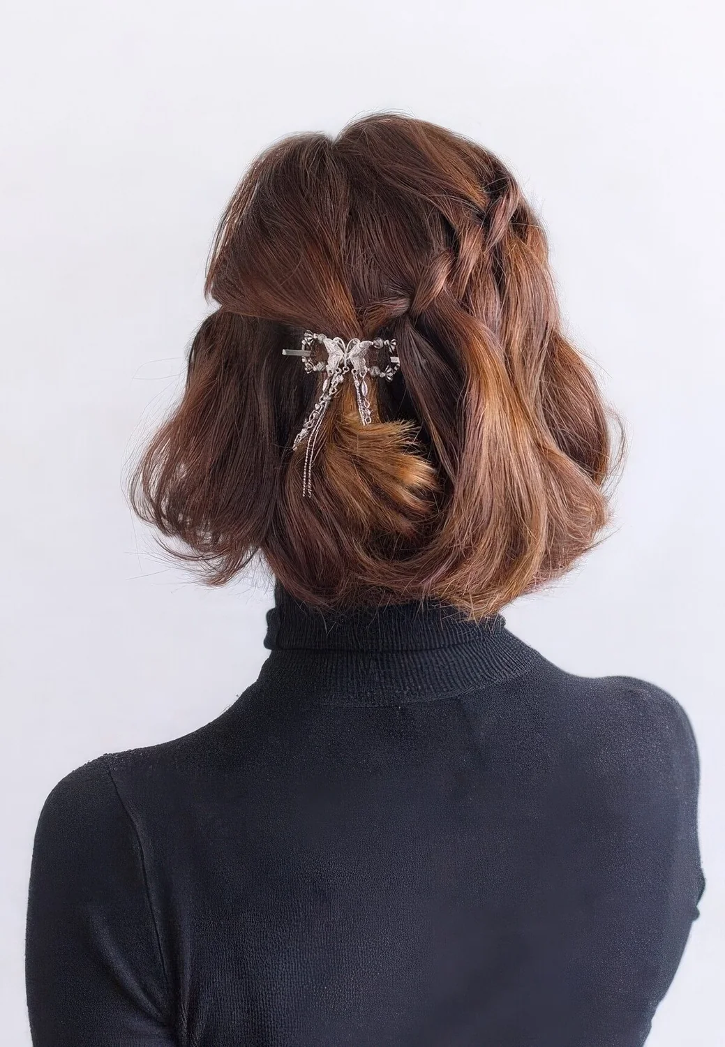 Half updo with a braid on one side and twist on the other, with waves down and a shiny hair piece.