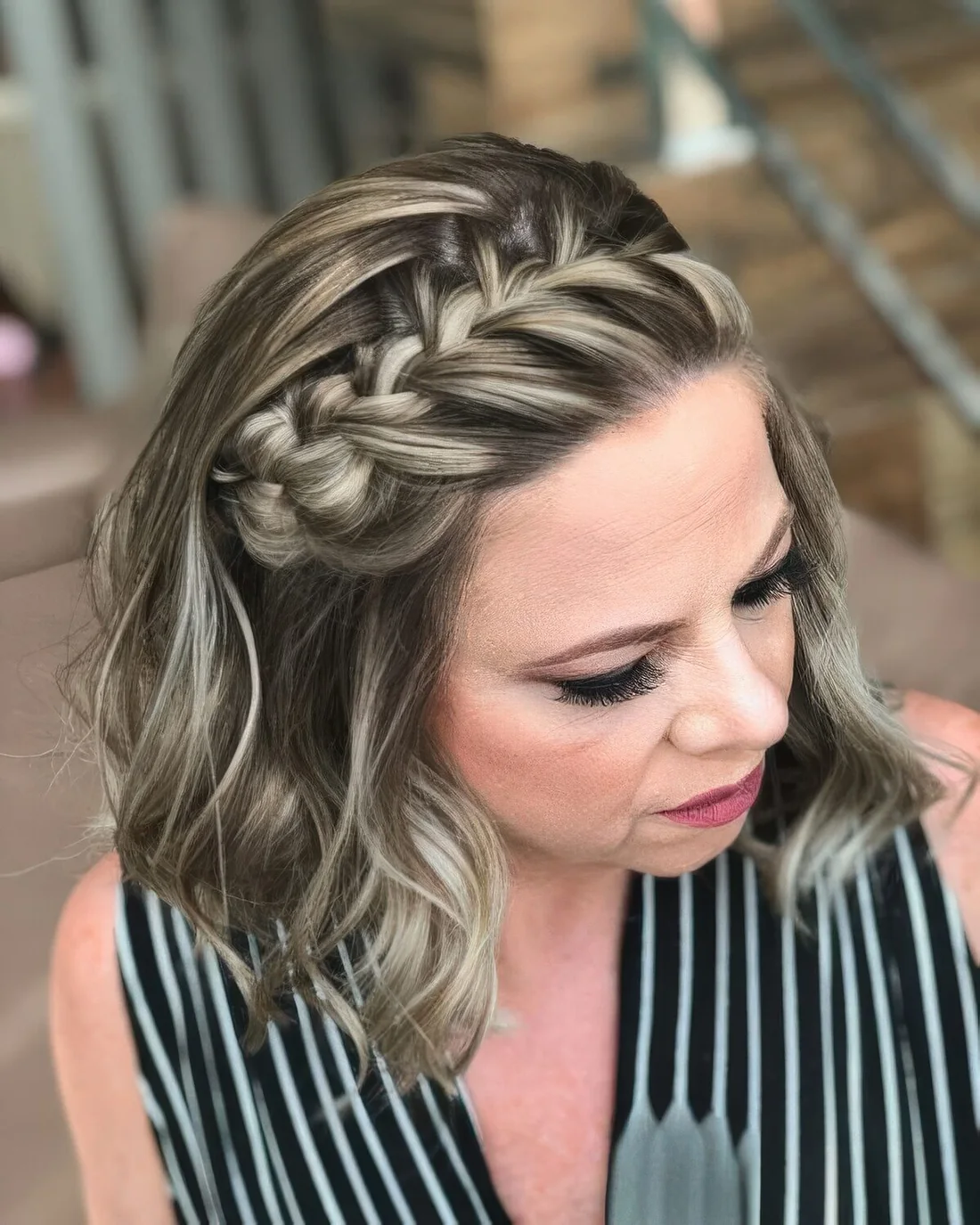 Half updo with a large braid from the center to the side and waves down.