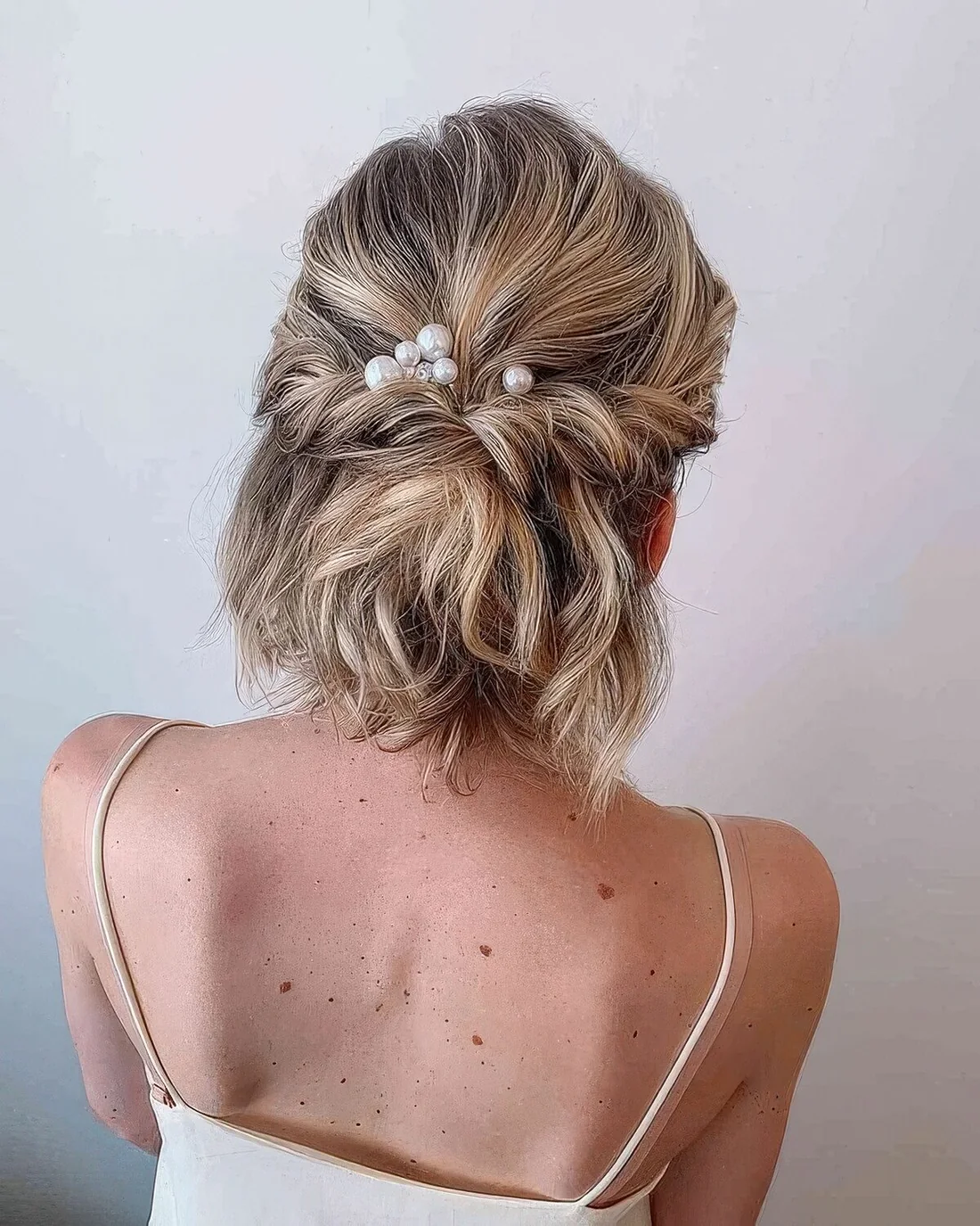 Half updo with a bump on top and twists and waves and pearl hair pins.