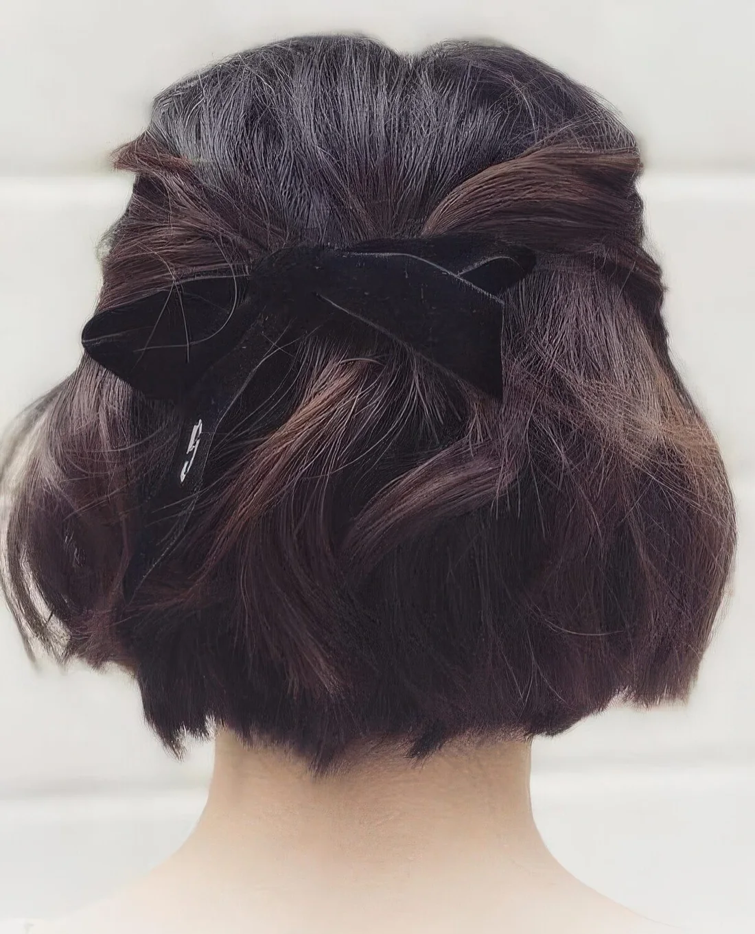 Half updo with twisted touches, a lot of volume and waves, a black velvet ribbon bow.