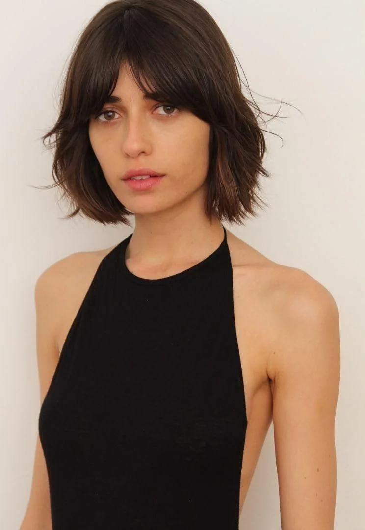 A smooth chocolate bob meets the jaw with rounded bottleneck bangs and lightly kicked ends