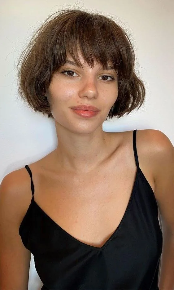 A rounded brown French bob sits near the jaw with fine Birkin bangs and gently tucked sides