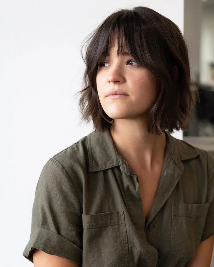 An airy brown bob pairs wispy bangs with longer cheekbone pieces and softly flicked ends