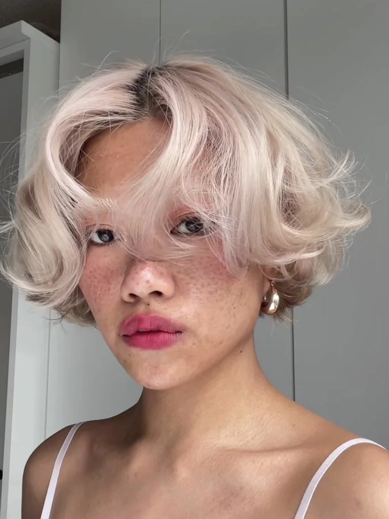 A platinum bob sits above the jaw with a long side fringe and airy ends flipped away from the face