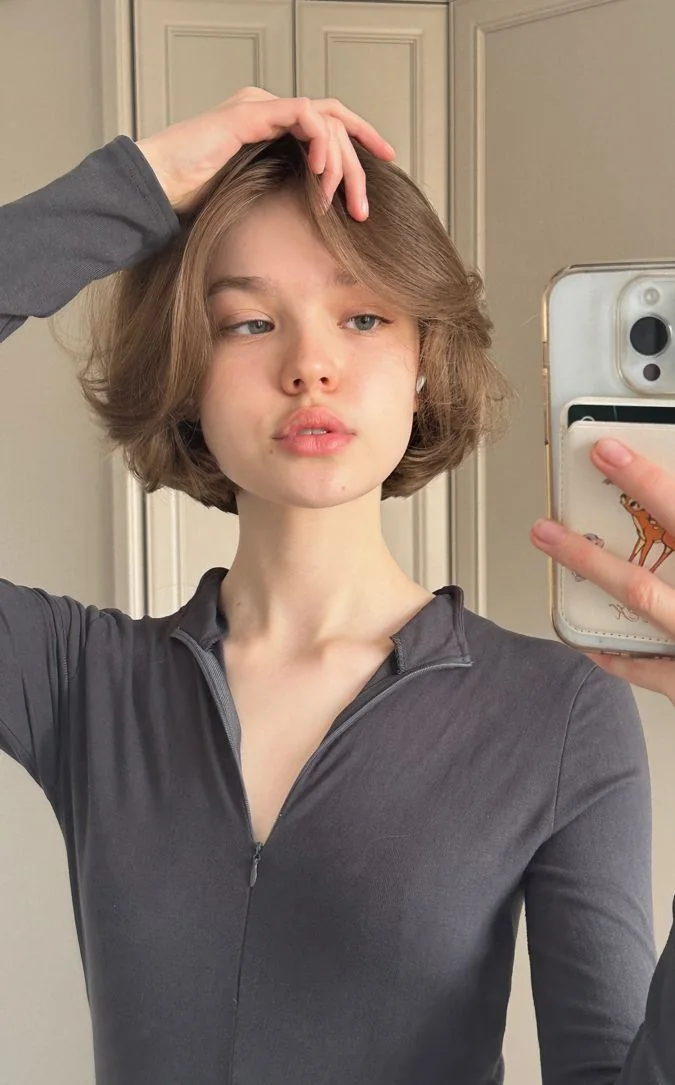 A mushroom brown bob has center parted front layers, a rounded crown, and ends tucked beneath the jaw