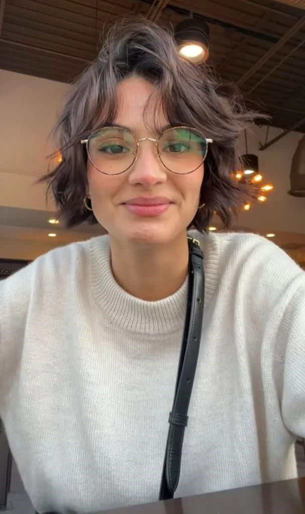 A brown ear length bob has a soft center part, uneven bends, and loose pieces around the ears