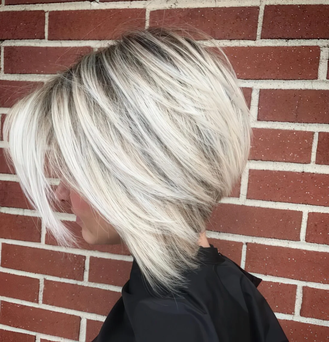 Chic blonde layered bob with a dark root for depth and a touch of drama.