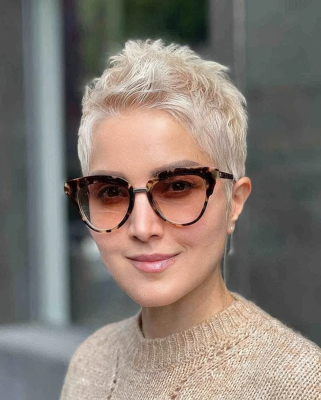 Creamy blonde pixie cut with styling on the top.