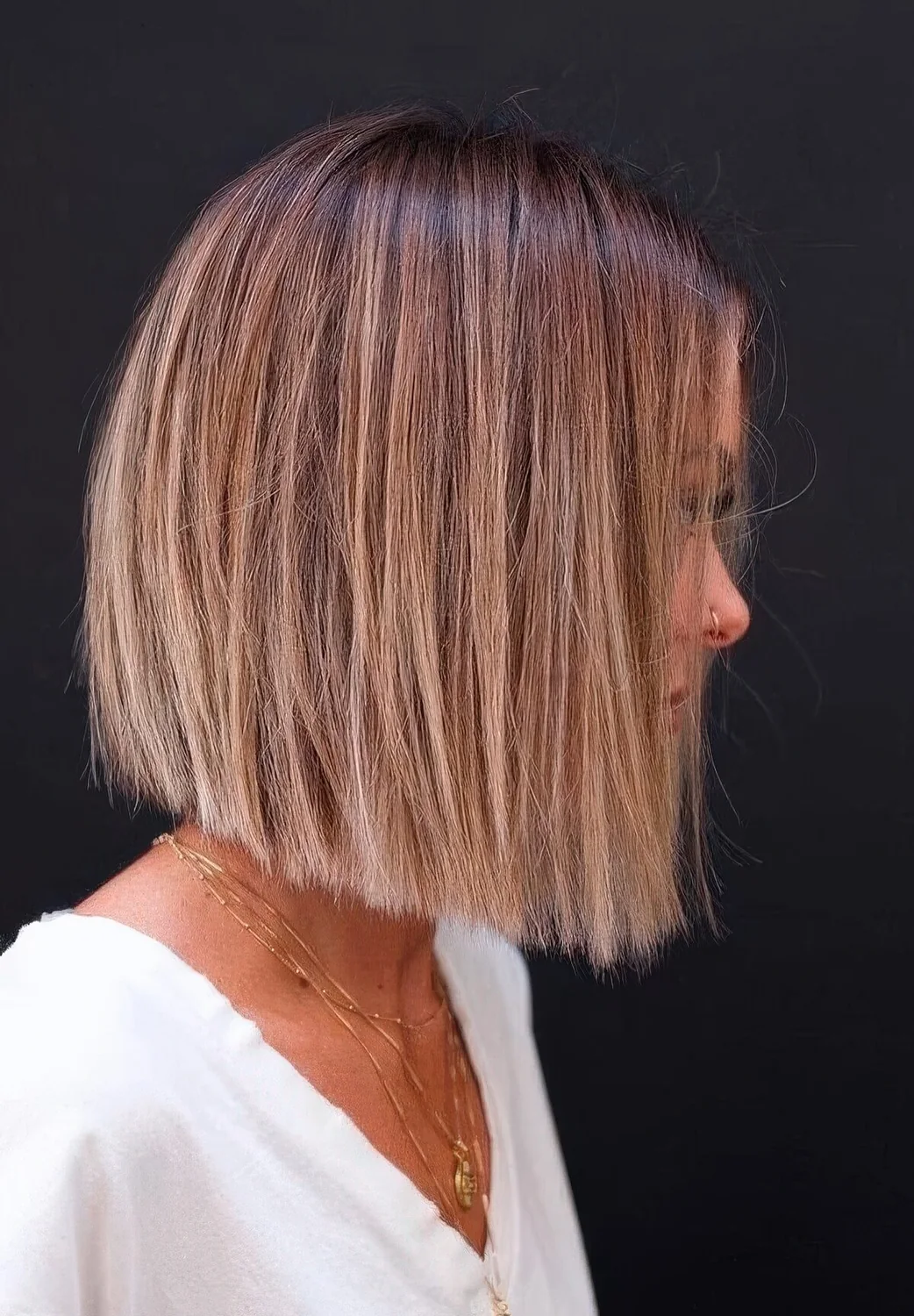 Chic blunt bob with a brown root and blonde balayage.