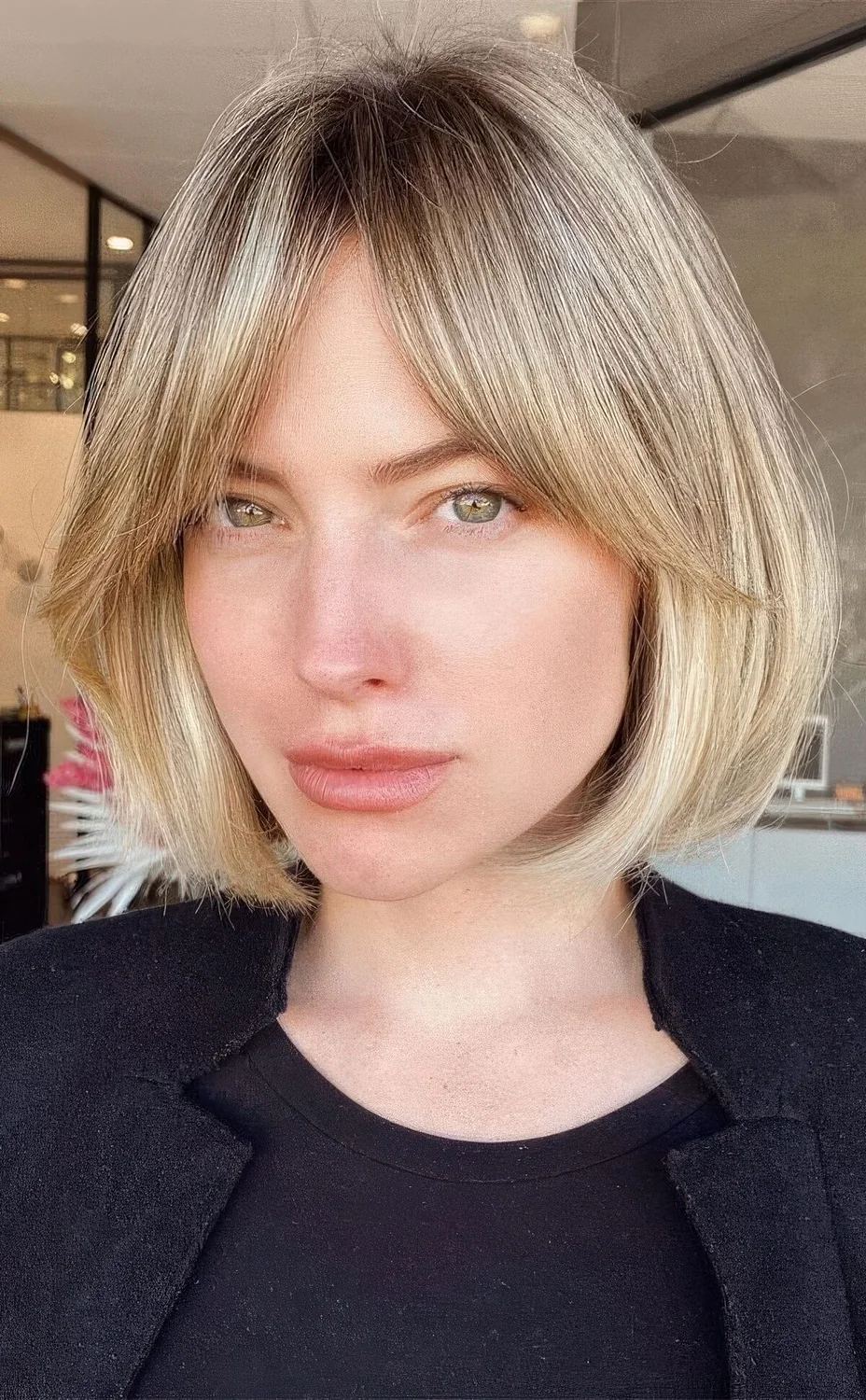 Blonde bob with a darker root and soft curtain bangs.