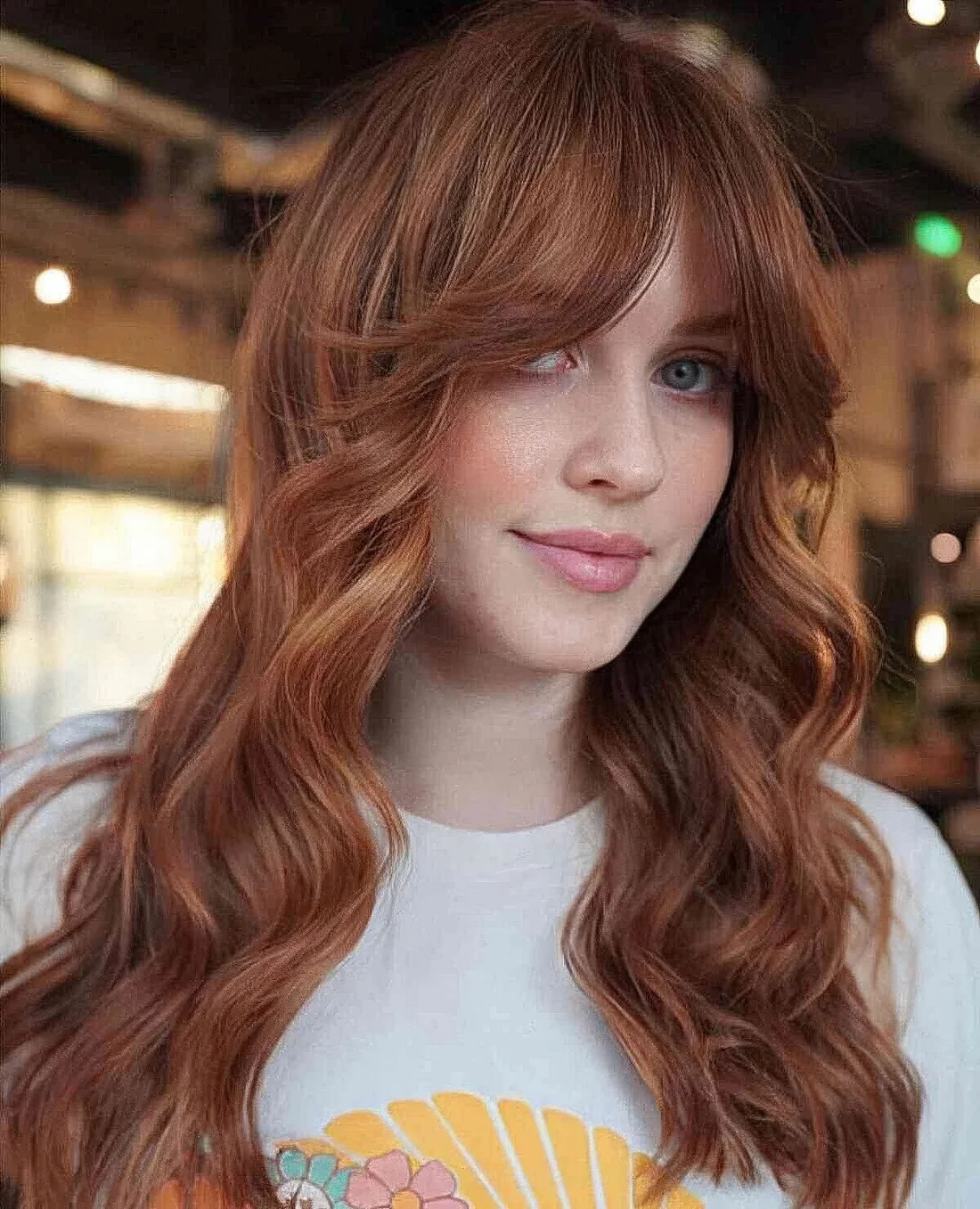 Long ginger hair with shaggy layers and waves plus a soft curtain fringe that accents the eyes.