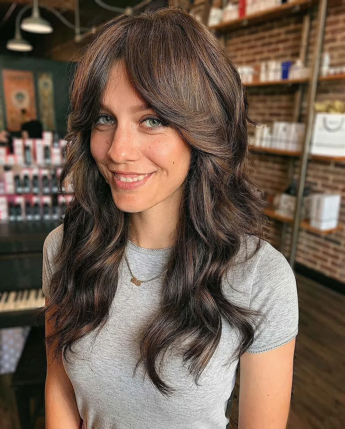 Long dark brown shaggy hair with long curtain bangs and dimensional highlights.