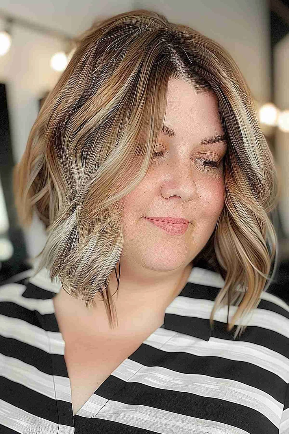Blonde wavy lob with dark roots and airy texture.