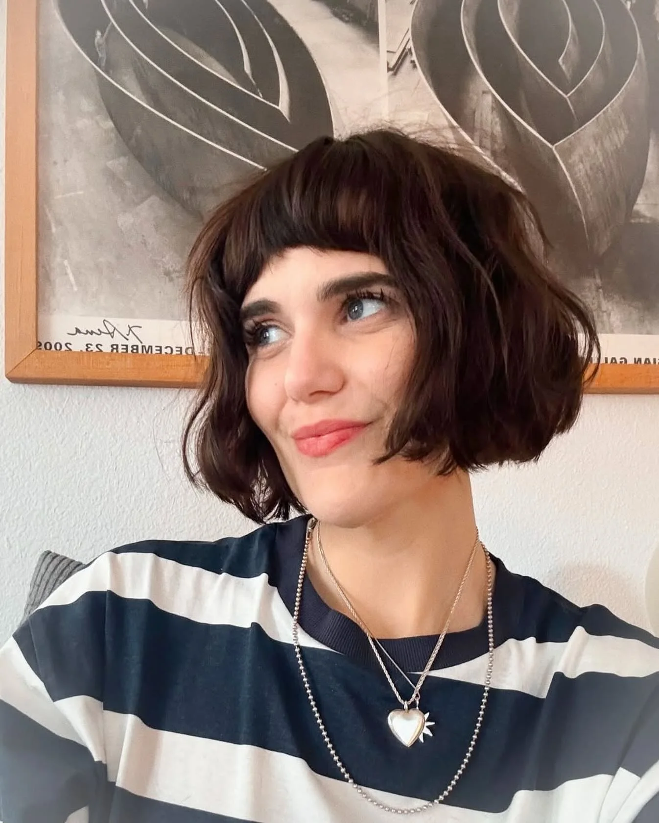 Woman with a rounded brunette bob, short blunt fringe, and softly curved jaw-length ends