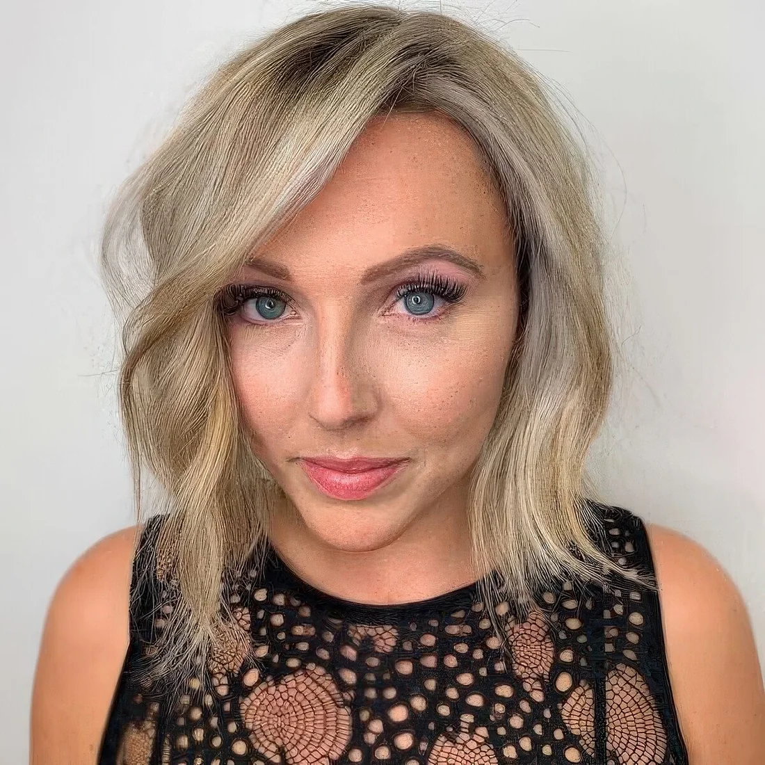 Blonde blunt bob with balayage and side part plus waves that make your hair look thicker.
