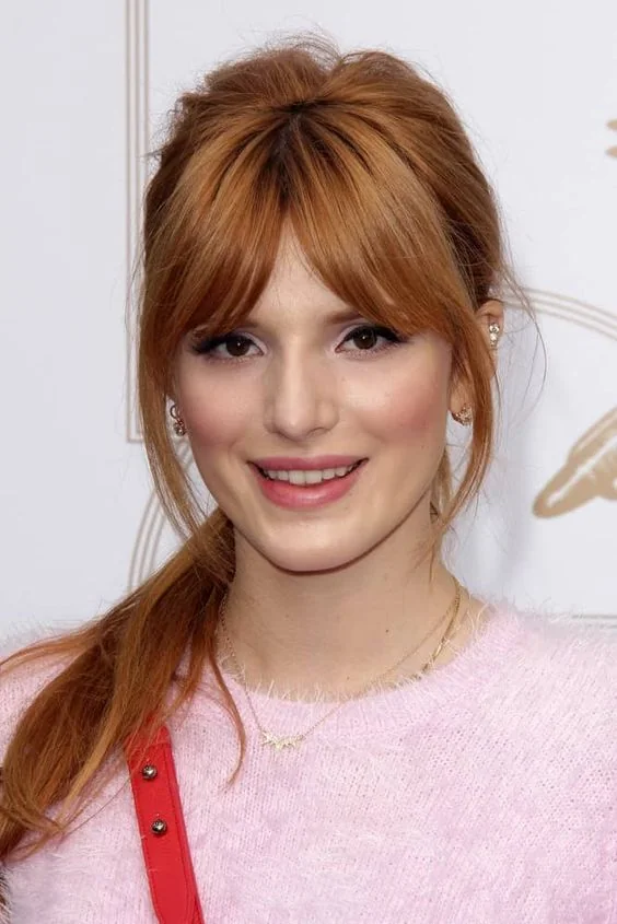 Ginger red hair in a ponytail with some volume on top and beautiful layered banfs.