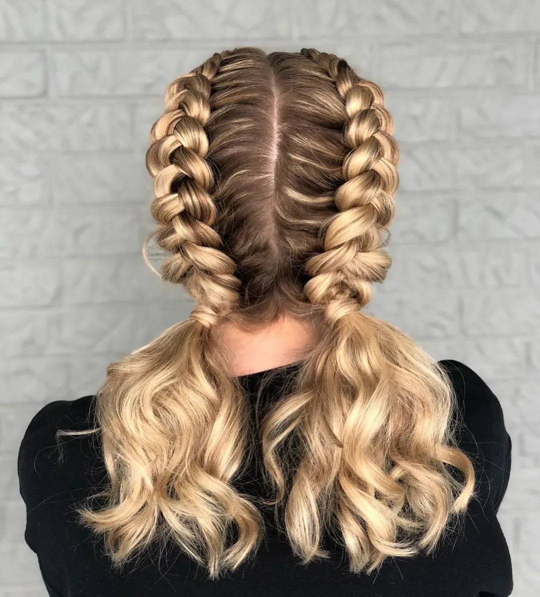 Back view of blonde double Dutch braids opening into loose waves