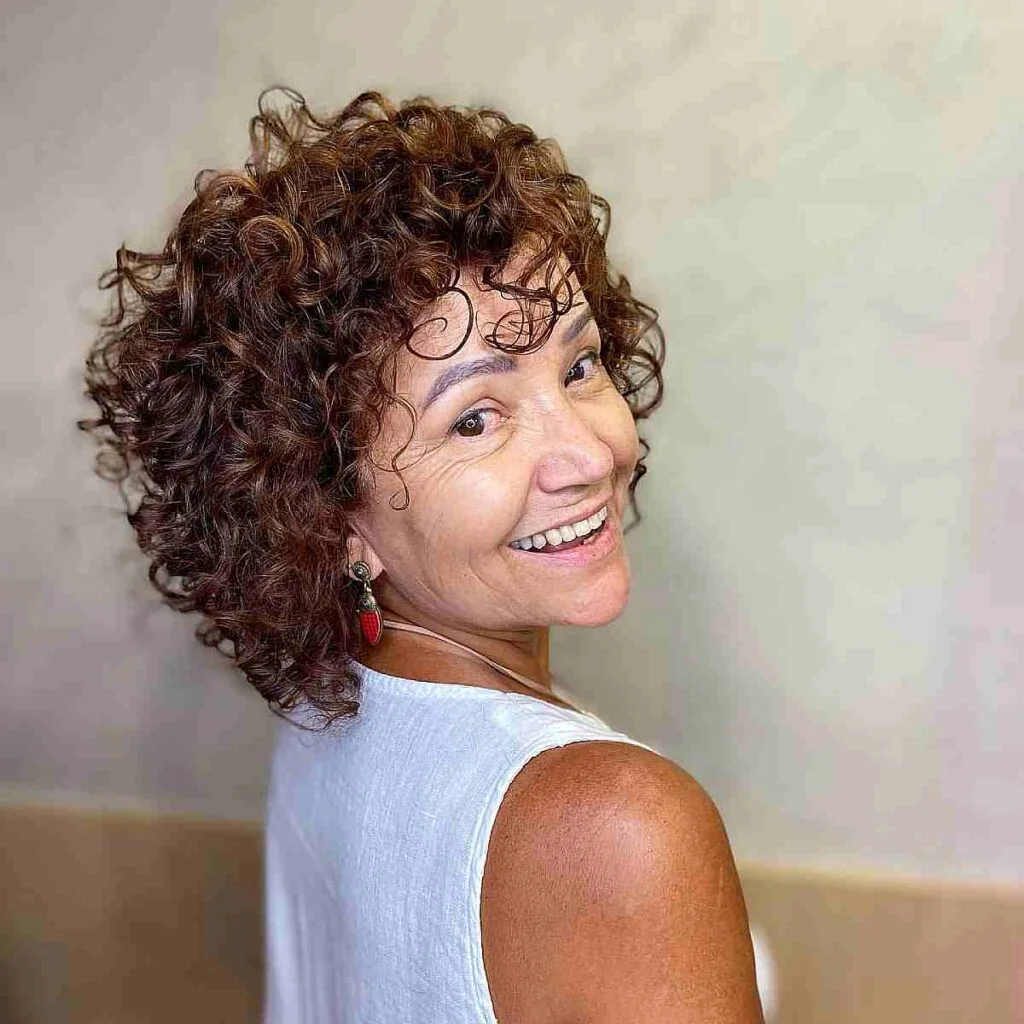 shoulder curly brunette shag with curly fringe fringe shown as a wash and wear haircuts for women over 60 idea, featuring center part
