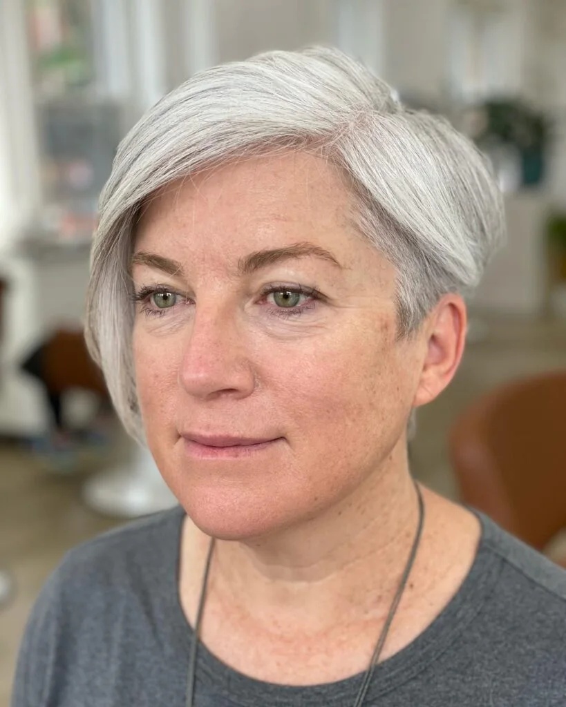 Older woman with a smooth silver side-swept pixie and tapered side