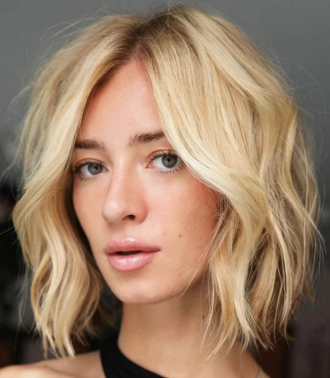 Textural blonde medium bob with side part and shaggy layers.