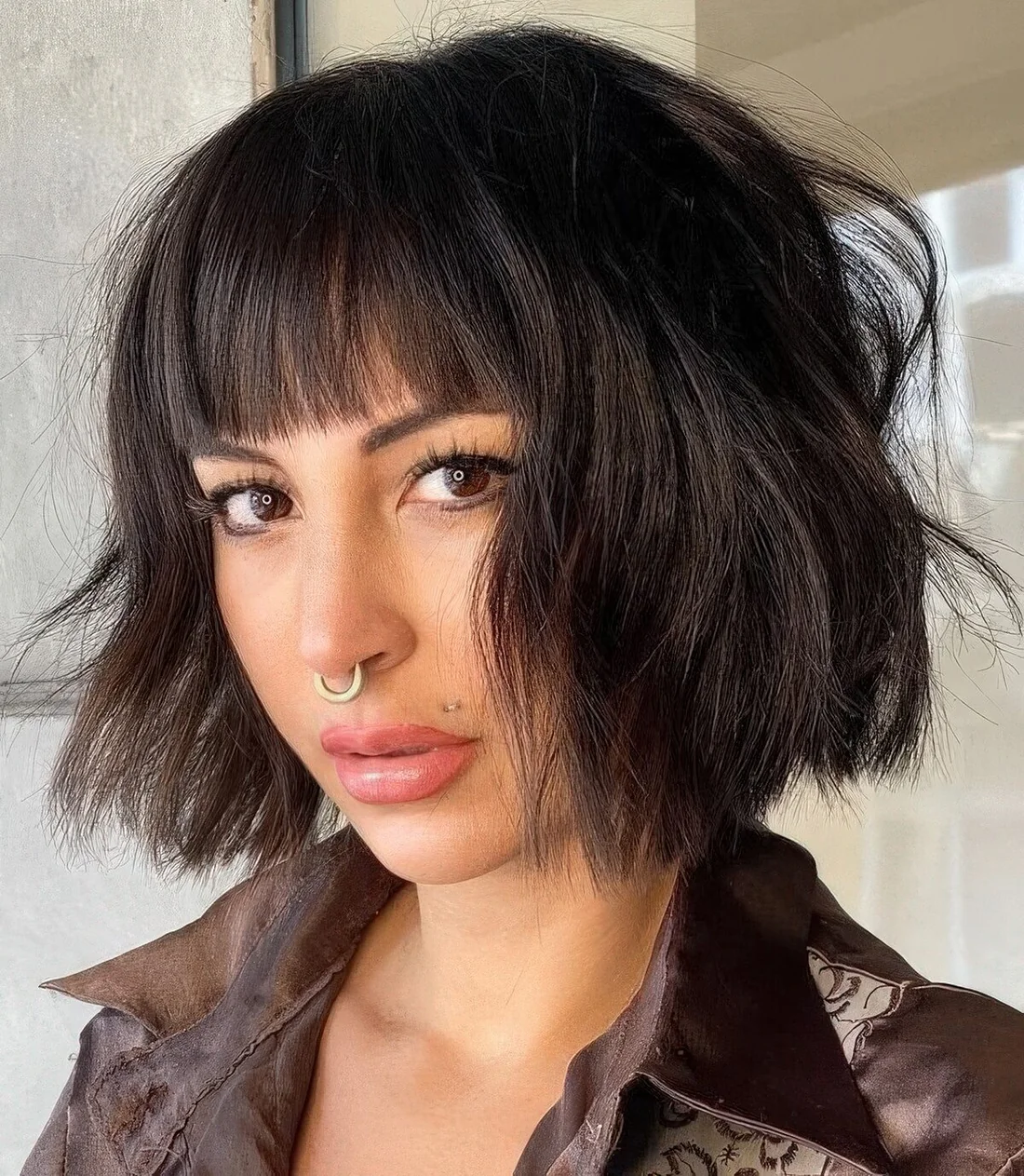 Black textural and wavy chin-length bob with waves and blunt bangs.