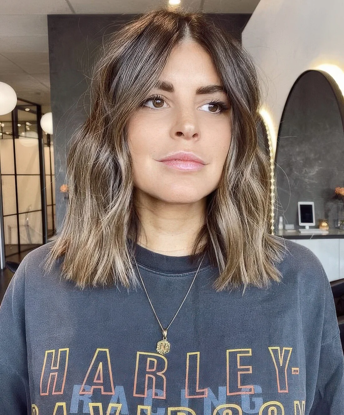 Brown outgrown bob with blonde balayage, with waves and center part.