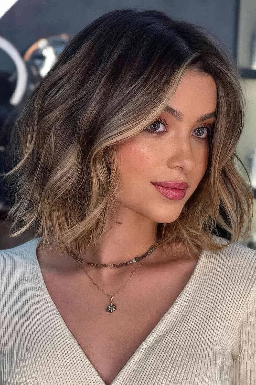 Long light brunette bob with honey balayage, middle part and loose waves.