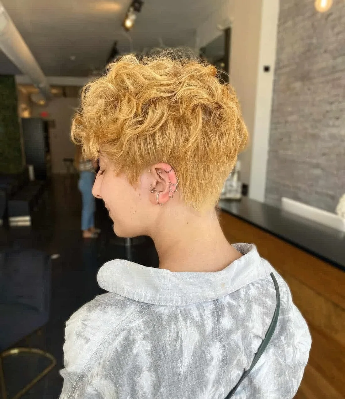 Tapered wavy pixie with bold edges and softness to bring the bulk of the curl towards the face.