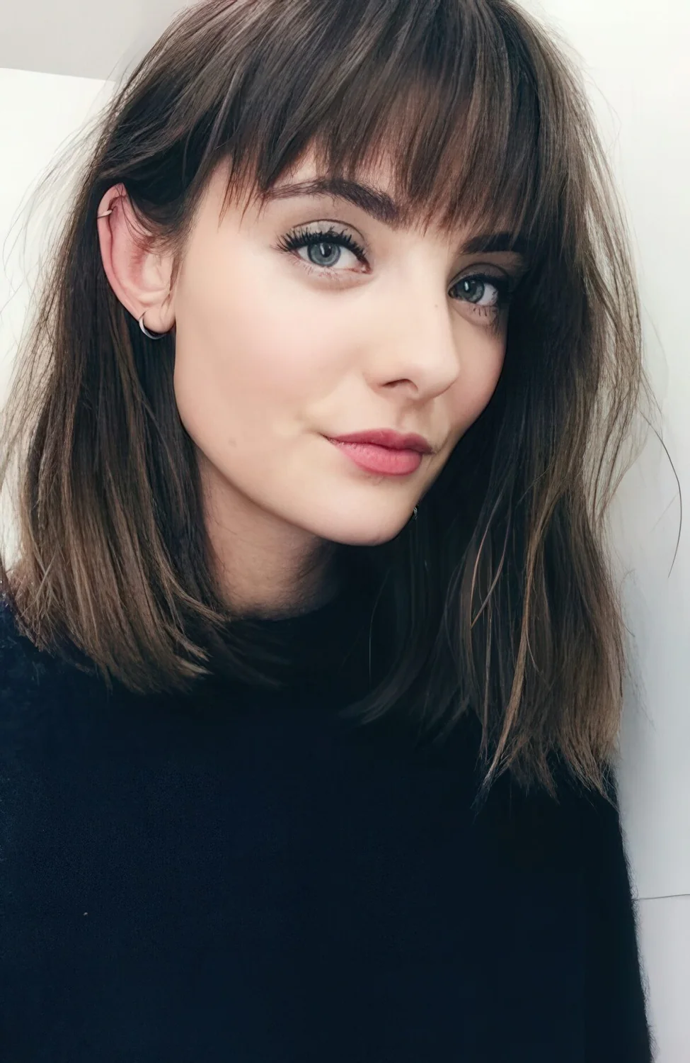 Dark messy long bob with light highlights and a fringe.
