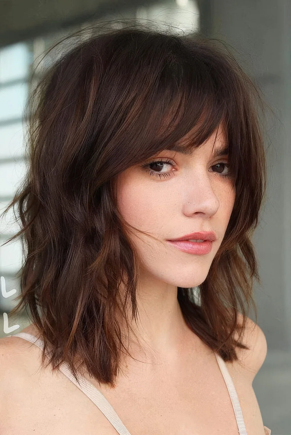 Shaggy and wavy dark chestnut long bob with a 70s inspired curtain fringe.