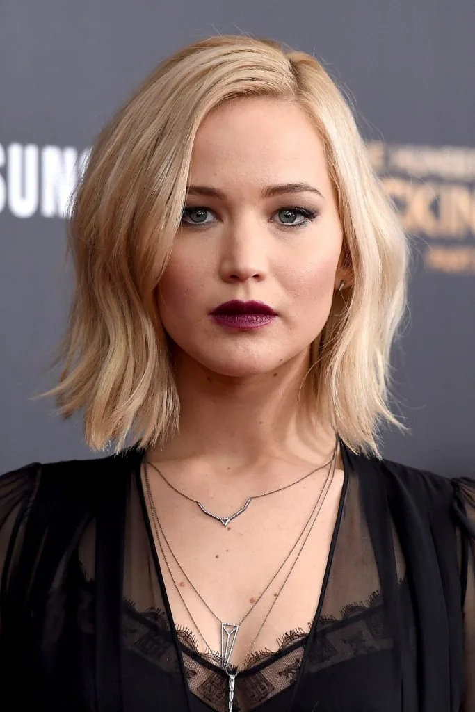 Blonde textured long bob with a deep side part and softly flipped ends.