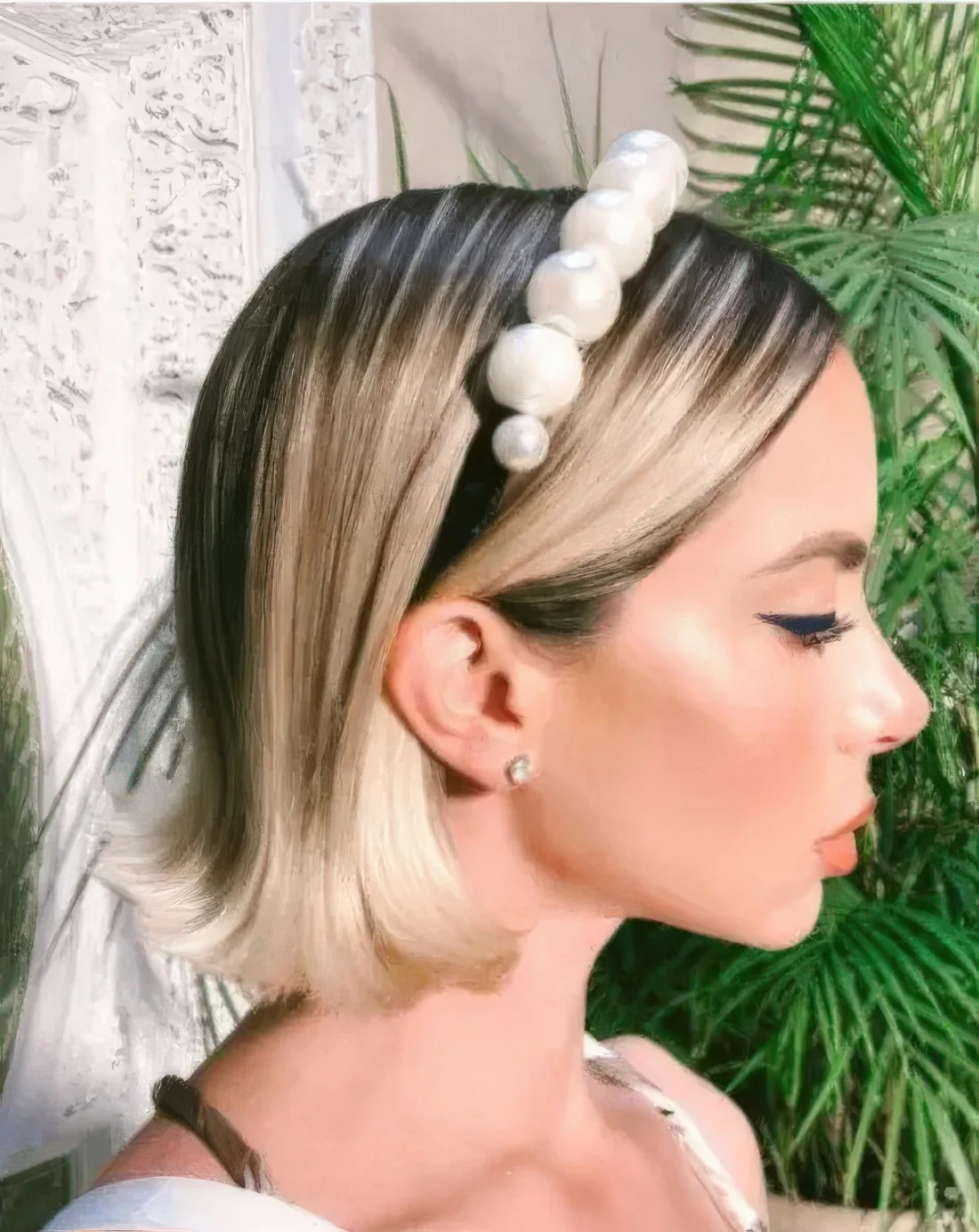 Long bob with blonde balayage, a darker root and rounded ends plus an oversized pearl headband.