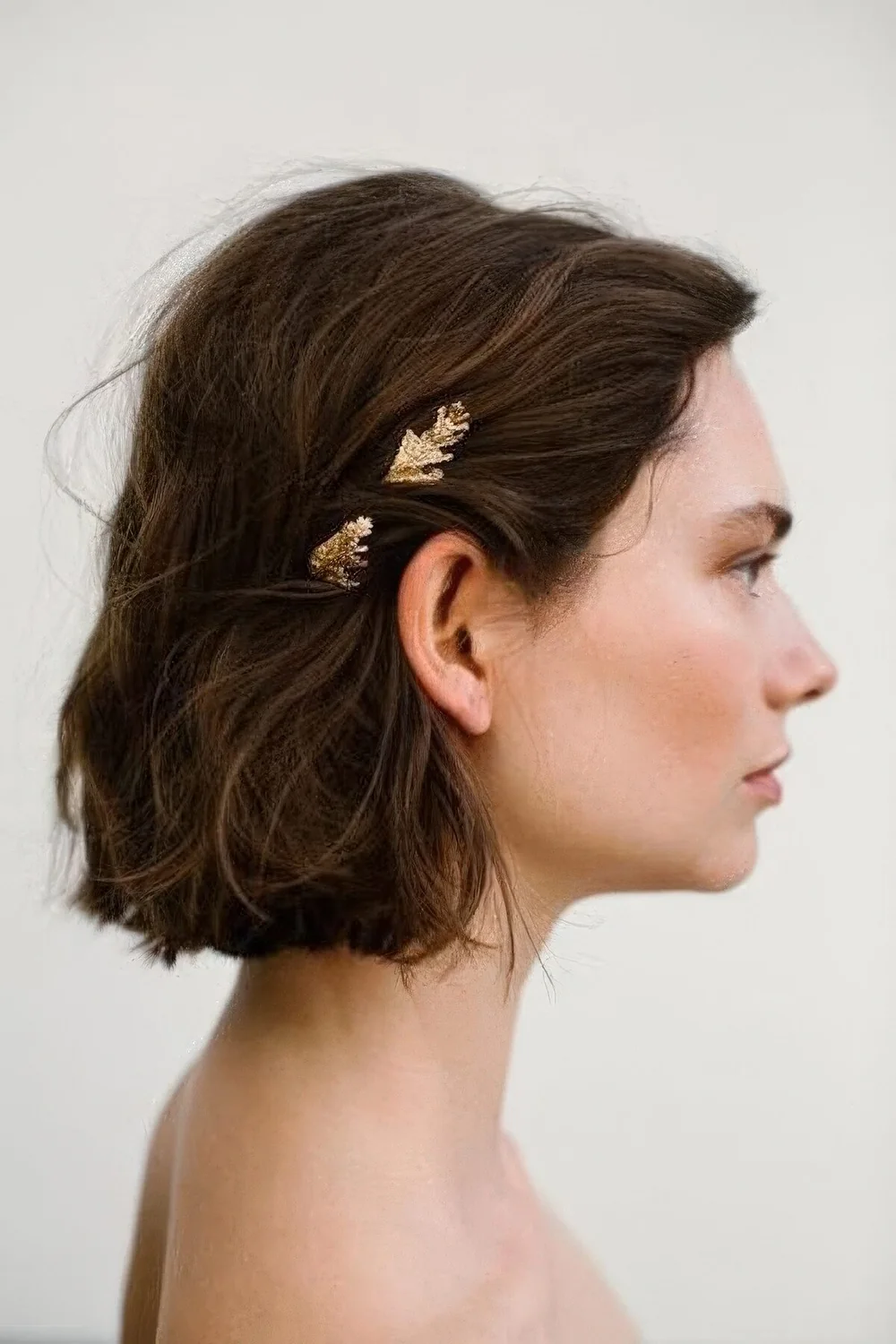 Messy textured and volumetric bob with a gold hairpiece for an accent.