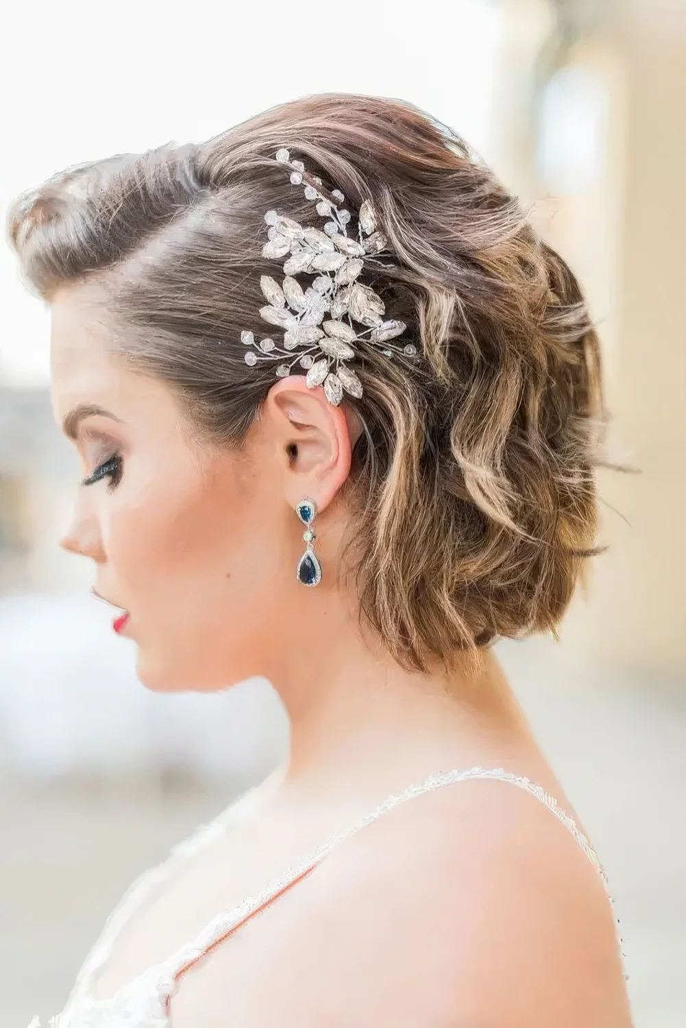 Mid brown bob with caramel balayage, side part and a large rhinestone hair piece.